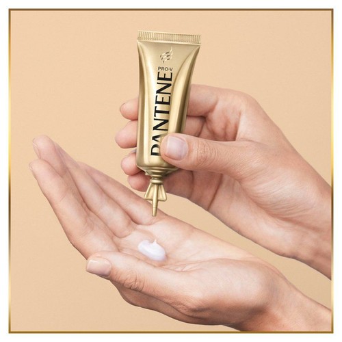 Złota tubka Pantene Pro-V, biały krem wyciskany na otwartą dłoń.