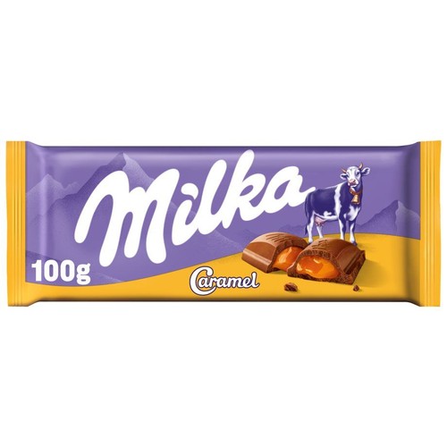Produkt: czekolada Milka Caramel 100g. Opakowanie jest fioletowe z białym napisem Milka i grafiką krowy. Obok niej leżą dwa kawałki czekolady, jeden z nich jest przełamany, ukazując karmelowe nadzienie. Tło górskie.