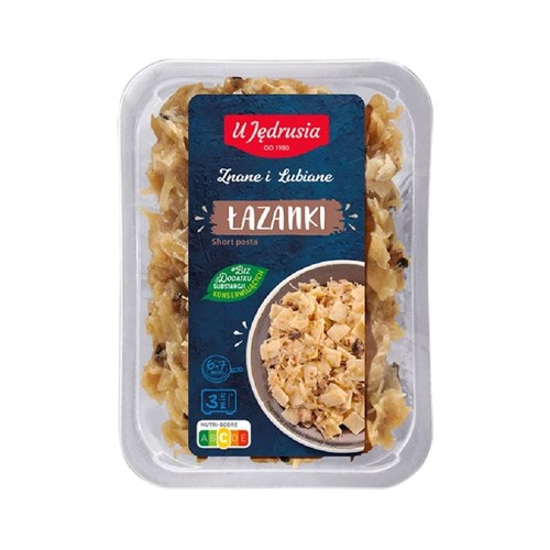 Gotowe danie U Jędrusia Łazanki w plastikowym pojemniku. Produkt to makaron z kapustą. Etykieta zawiera logo U Jędrusia, nazwę "Łazanki", informację o braku konserwantów i czasie przygotowania 6-7 minut na patelni lub 3 minutach w mikrofali.