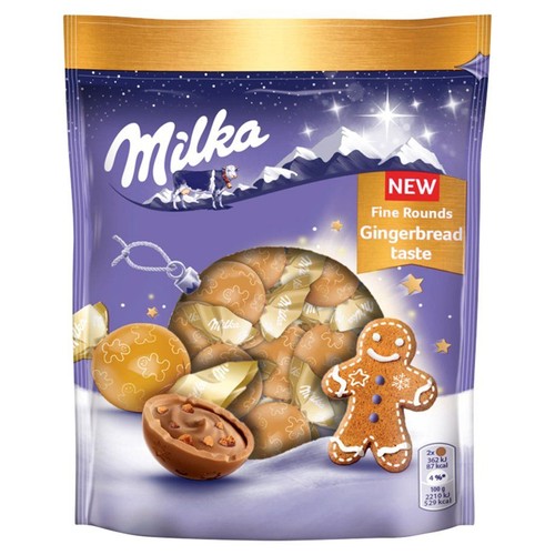 Produkt Milka Fine Rounds o smaku piernikowym w fioletowej torebce z zimowym motywem. Widoczne są ilustracje czekoladowych kulek, w tym jedna otwarta z nadzieniem, oraz uśmiechnięty piernikowy ludzik. Etykieta informuje o nowym smaku.