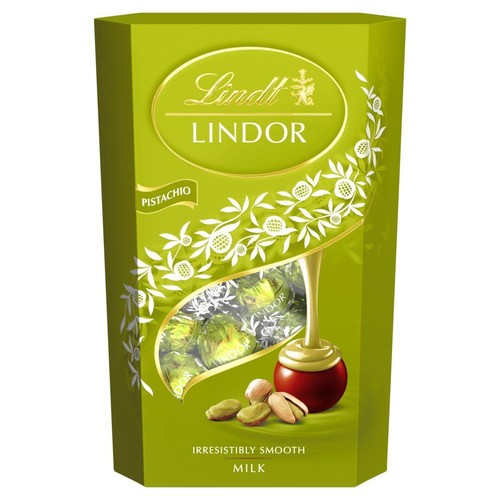 Zielone, sześciokątne opakowanie czekoladek Lindt Lindor Pistacjowe. Na froncie złote logo, nazwa smaku oraz okienko z widocznymi zielonymi pralinkami. Grafika przedstawia pralinkę z wypływającym kremowym nadzieniem i orzechy pistacjowe.