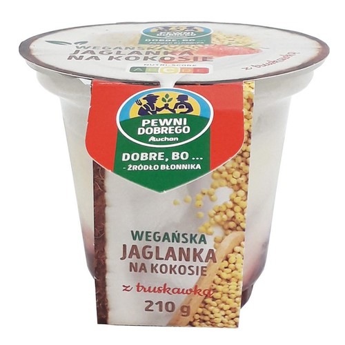 Przezroczysty kubek z wegańską jaglanką na kokosie i truskawką, 210g. Na etykiecie logo Pewni Dobrego Auchan i informacja "źródło błonnika". Widoczne ziarna prosa i drewniana łyżka na grafice.