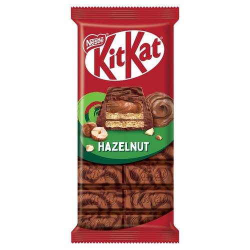Produkt: baton Kit Kat o smaku orzechowym. Czerwone opakowanie z logo Nestle i Kit Kat. Na opakowaniu grafika przedstawiająca przekrój batonika z waflem i kremem, obok całe i posiekane orzechy laskowe. Widoczna tekstura czekolady.