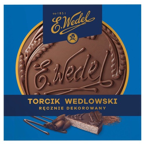 Niebieskie opakowanie Torcika Wedlowskiego E.Wedel. Na górze duży, okrągły czekoladowy medalion z wytłoczonym napisem E.Wedel i datą "od 1851". Poniżej grafika kawałka tortu z warstwami, polewą czekoladową i czekoladowymi dekoracjami.