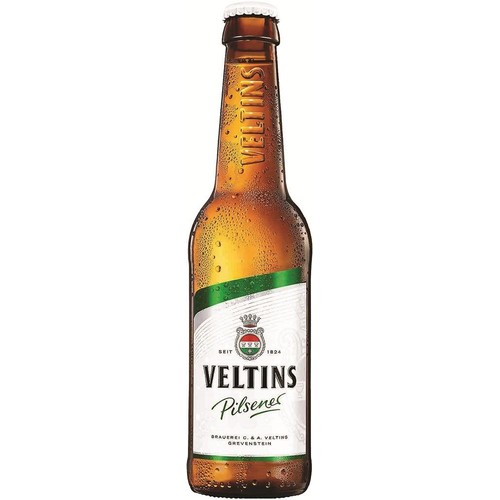 Butelka piwa Veltins Pilsener z brązowego szkła, z białą etykietą i zielonym akcentem. Na etykiecie znajduje się nazwa Veltins, typ Pilsener, herb browaru z koroną oraz informacja "Browar C. & A. Veltins Grevenstein". Butelka jest zaparowana.