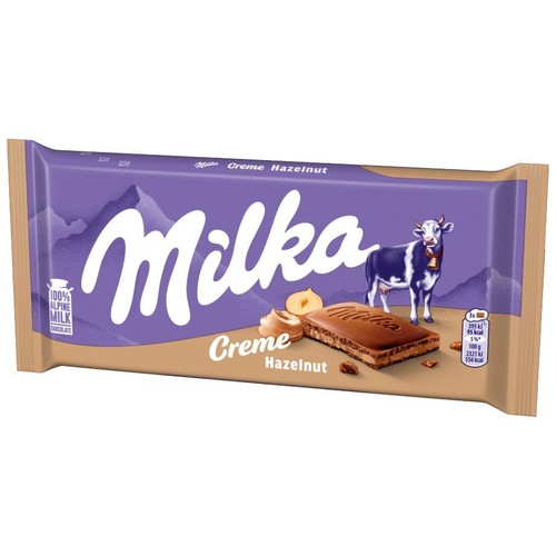Czekolada Milka Krem Orzechowy w fioletowym opakowaniu. Widoczna grafika przedstawiająca białą krowę Milka, góry, kawałek czekolady z nadzieniem orzechowym i całe orzechy laskowe. Na opakowaniu napis "100% czekolada z mleka alpejskiego".