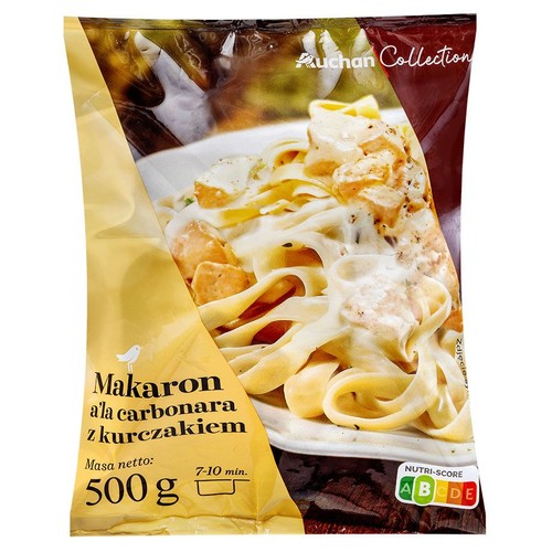 Produkt Auchan Collection: makaron a'la carbonara z kurczakiem w opakowaniu 500 g. Na opakowaniu widoczne jest zdjęcie przedstawiające ugotowany makaron tagliatelle z kremowym sosem i kawałkami kurczaka. Sugerowany czas przygotowania to 7-10 minut.
