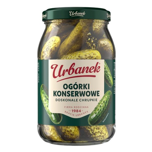 Słoik ogórków konserwowych Urbanek z ciemnozieloną zakrętką. Na etykiecie widnieje nazwa produktu "Ogórki Konserwowe Doskonałe Chrupkie". Jest to produkt rodzinnej firmy Urbanek, założonej w 1984 roku. W słoiku są całe ogórki.