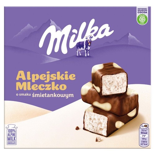 Fioletowe opakowanie Milka Alpejskie Mleczko o smaku śmietankowym. Na pudełku logo Milka, krowa i góry. Na pierwszym planie trzy czekoladowe cukierki z białym, puszystym wnętrzem, pokryte ciemną czekoladą z jasnymi plamkami.