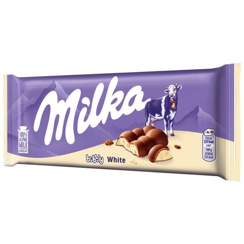 Fioletowo-białe opakowanie czekolady Milka Bubbly White 100g. Na opakowaniu logo Milka, fioletowa krowa na tle gór. Obok grafika przedstawiająca przekrojone kostki czekolady mlecznej z bąbelkowym, białym nadzieniem.