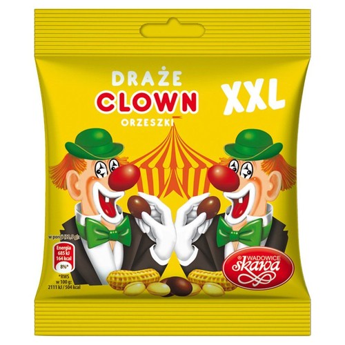 Żółte opakowanie draży orzeszkowych "Draże Clown Orzeszki XXL" firmy Skawa. Na froncie grafika przedstawiająca dwóch uśmiechniętych klaunów w zielonych kapeluszach, trzymających orzeszki ziemne w czekoladzie. Widoczne również orzeszki ziemne.