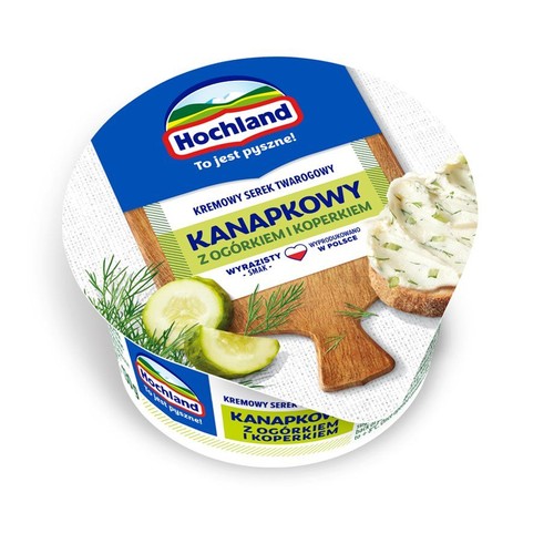 Okrągłe opakowanie serka Hochland Kanapkowy z ogórkiem i koperkiem. Na wieczku grafika z ogórkiem, koperkiem i posmarowaną kanapką.