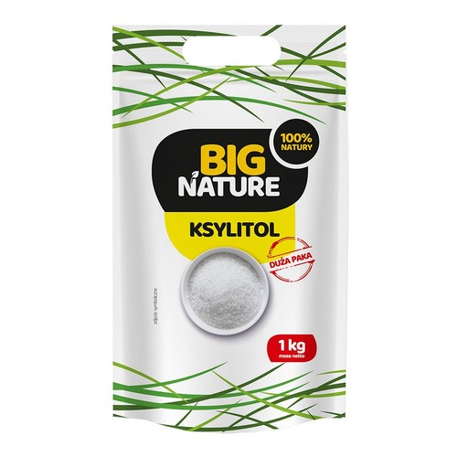 Biała torebka ksylitolu Big Nature o masie netto 1 kg. Opakowanie ozdobione zielonymi grafikami przypominającymi trawę. Na etykiecie widnieje napis "100% Natury" oraz "Duża Paka". Grafika przedstawia miseczkę z białym granulatem.