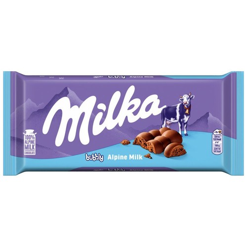 Tabliczka czekolady Milka Bubbly Alpine Milk w fioletowym opakowaniu. Widoczna jest krowa Milka, alpejskie góry w tle oraz rozłamane kawałki bąbelkowej czekolady mlecznej. Etykieta informuje o 100% mleku alpejskim.