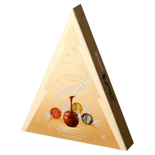 Złote, trójkątne pudełko czekoladek Lindt Lindor, z napisem "Irresistibly Smooth" (nieodparcie gładkie) i "Assorted" (różnorodne). Opakowanie ma świąteczny motyw z płatkami śniegu i grafikami czekoladek, w tym jednej z wylewającą się czekoladą.