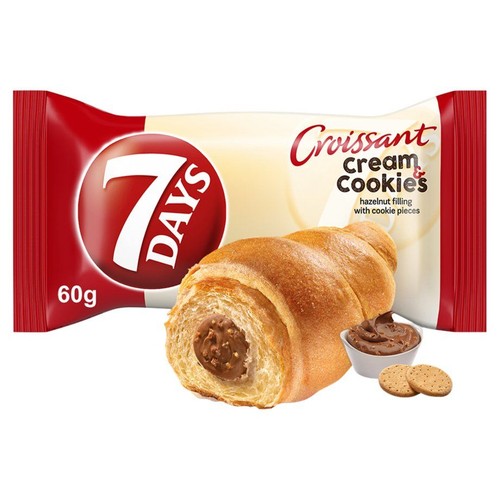 Rogalik 7 DAYS Croissant Cream Cookies 60g z nadzieniem orzechowym i kawałkami ciasteczek. Obok miseczka kremu i dwa ciasteczka.