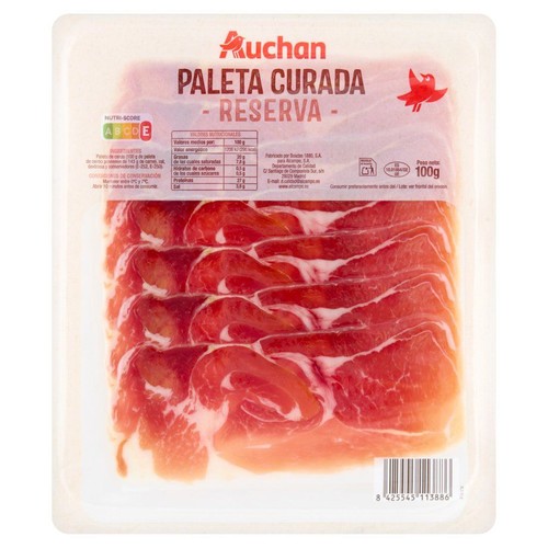 Przezroczyste opakowanie z dojrzewającą łopatką wieprzową Auchan Paleta Curada Reserva, o wadze 100g. Wewnątrz ułożone są cienkie plastry czerwonego mięsa z białym tłuszczem. Na etykiecie logo Auchan i nazwa produktu.