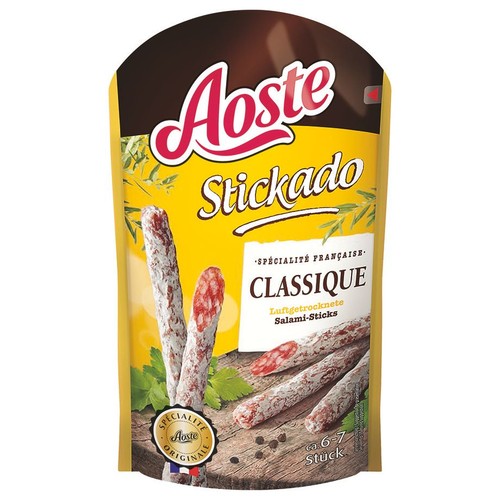 Żółto-brązowe opakowanie Aoste Stickado, klasyczne suszone paluszki salami, francuska specjalność. Na etykiecie widoczne są całe i pokrojone paluszki salami ułożone na drewnianej desce z ziołami i czarnym pieprzem. Opakowanie zawiera ok. 6-7 sztuk.