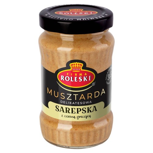 Produkt Roleski: musztarda Sarepska z dodatkiem czarnej gorczycy, zapakowana w przezroczysty szklany słoik. Etykieta jest czarna ze złotymi i białymi napisami. Czarna zakrętka z logo.