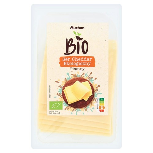 Opakowanie sera cheddar Auchan BIO, krojonego w plastry. Widoczne logo ekologiczne UE i nazwa producenta.