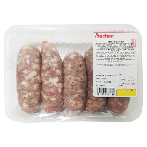 Pięć surowych kiełbas majerankowych marki Auchan, ułożonych w przezroczystej plastikowej tacce. Kiełbasy mają jasnoróżowy kolor z widocznymi kawałkami mięsa i przyprawami. Na opakowaniu biała etykieta z nazwą produktu i składem.