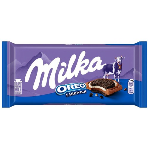 Opakowanie czekolady Milka Oreo Sandwich w kolorze fioletowym. Widoczny jest duży napis Milka, wizerunek krowy, góry i grafika przedstawiająca czekoladę z nadzieniem Oreo. Produkt zawiera 100% alpejskiego mleka.