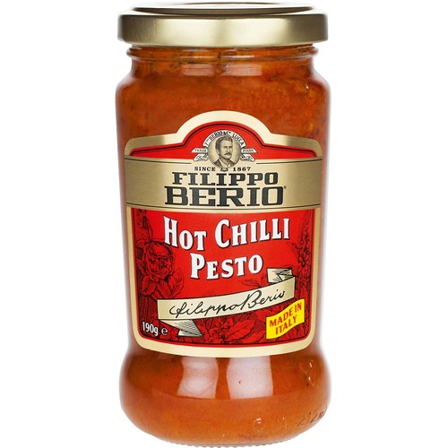 Produkt Filippo Berio: Ostre Pesto Chili w przezroczystym szklanym słoiku ze złotą zakrętką. Czerwona etykieta z ozdobnym wzorem roślinnym, portretem założyciela, rokiem "Od 1867" i napisem "Wyprodukowano we Włoszech". Zawartość 190g.
