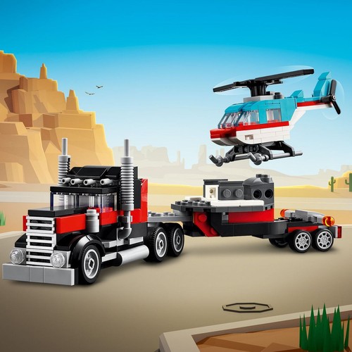 Scena z klocków LEGO, gdzie głównym elementem jest duża, czarno-czerwona ciężarówka z naczepą. Obok niej, w powietrzu, leci niebiesko-biały helikopter. Całość osadzona jest w scenerii pustynnej z charakterystycznymi skałami.