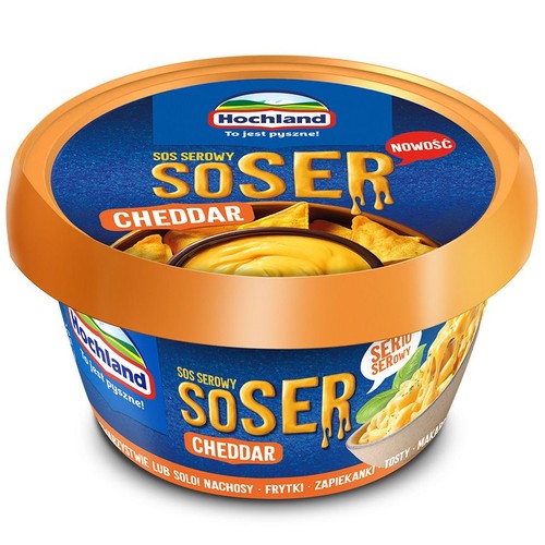 Hochland Sos Serowy SOSER Cheddar w okrągłym opakowaniu z pomarańczową pokrywką. Na etykiecie grafika sosu z nachosami.