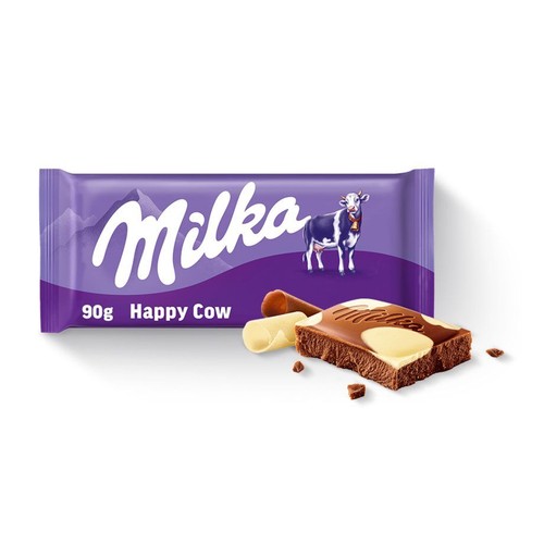 Fioletowe opakowanie czekolady Milka 90g z logo marki, napisem "Happy Cow" i grafiką krowy. Obok leży przełamany kawałek czekolady, ukazujący warstwy czekolady mlecznej i białej, z widocznym logo Milka na wierzchu. W tle drobne okruszki.