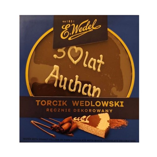 Opakowanie E.Wedel Torcik Wedlowski, ręcznie dekorowany. Na ciemnej czekoladzie tortu widoczny biały napis "30 lat Auchan". Poniżej grafika wafla z nadzieniem orzechowym w ciemnej czekoladzie z dekoracją z białej czekolady.
