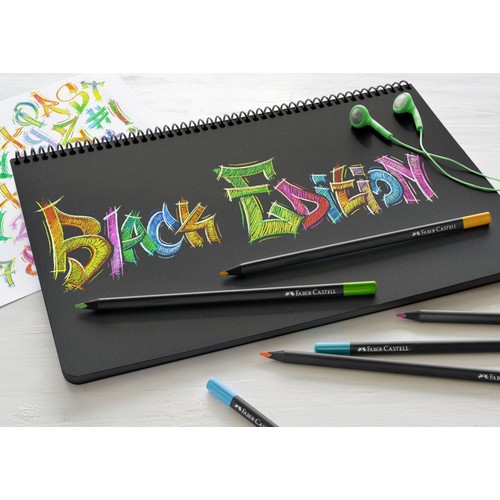 Czarny notatnik spiralny leży na jasnym blacie. Na jego czarnych kartkach widnieje napis "BLACK EDITION" wykonany kolorowymi kredkami w stylu graffiti. Obok notatnika leżą kredki Faber-Castell z różnokolorowymi końcówkami oraz zielone słuchawki douszne.