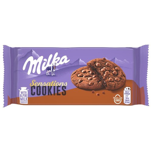 Opakowanie ciasteczek Milka Sensations. Fioletowe tło z górami, krowa Milka i dwa czekoladowe ciasteczka z kawałkami czekolady.