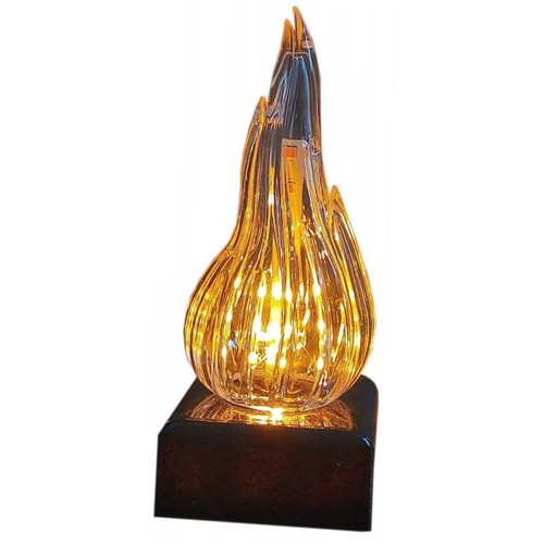 Lampa LED o unikalnym designie, imitującym płomień. Klosz z przezroczystego tworzywa ma pionowe żłobienia, które rozpraszają światło ciepłych diod LED, nadając mu dynamiczny wygląd. Stoi na solidnej, ciemnej, kwadratowej podstawie.