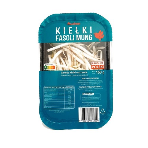 Świeże kiełki fasoli Mung Auchan w plastikowym opakowaniu. Etykieta w kolorze turkusowym z nazwą produktu i logo marki. Widoczne białe kiełki. Produkt warzywny, gotowy do spożycia, 150 gramów.
