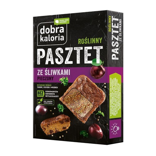 Dobra Kaloria Roślinny Pasztet Ze Śliwkami Pieczony w ciemnym opakowaniu. Na opakowaniu grafika przedstawiająca kawałek pasztetu z nasionami słonecznika, mniejszy kawałek z widocznymi śliwkami oraz całe śliwki. Produkt bez konserwantów i barwników.