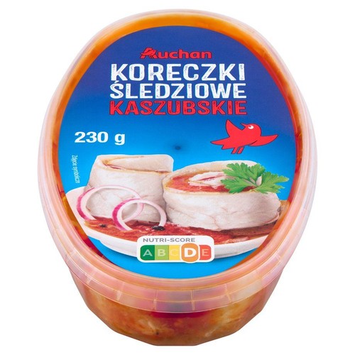 Owalne, plastikowe opakowanie Koreczków Śledziowych Kaszubskich marki Auchan, o wadze 230 g. Na niebieskiej etykiecie widnieje symboliczna grafika dwóch roladek śledziowych z czerwoną cebulą i zieloną natką pietruszki.