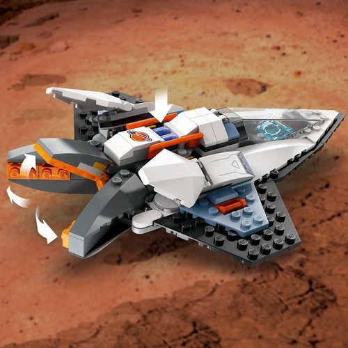 Złożony z klocków LEGO pojazd kosmiczny o aerodynamicznym kształcie, dominują białe, szare i pomarańczowe barwy. Widoczne są strzałki wskazujące na możliwość obracania lub wysuwania elementów. Tło stanowi pustynny, czerwonawy teren z drobnymi kamieniami.