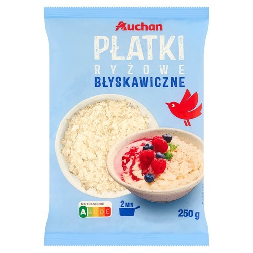 Niebieskie opakowanie płatków ryżowych błyskawicznych Auchan, 250 g. Widoczne miski z suchymi i gotowymi płatkami z owocami.