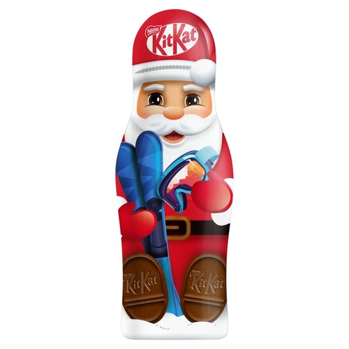 Produkt KitKat w świątecznym opakowaniu w kształcie Mikołaja. Mikołaj ma czerwoną czapkę z logo KitKat, białą brodę, czerwony strój, czarny pasek. Trzyma niebieskie narty i kolorowe gogle. U podstawy opakowania widoczne są dwa czekoladowe batoniki KitKat.