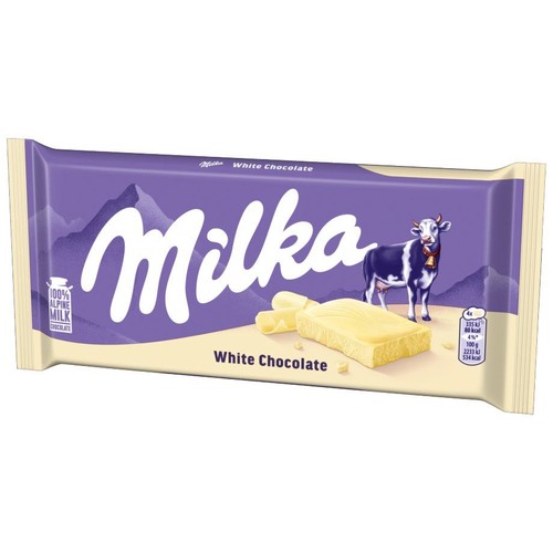 Fioletowo-białe opakowanie tabliczki Milka Biała Czekolada. Na etykiecie widnieje charakterystyczna krowa Milka oraz kawałek białej czekolady z wiórkami. Tło przedstawia góry. Produkt zawiera 100% mleka alpejskiego.