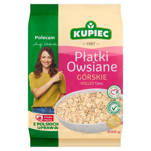 Opakowanie płatków owsianych Kupiec, 400g. Z wysoką zawartością błonnika. Na opakowaniu uśmiechnięta kobieta.