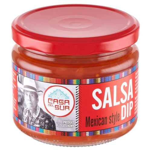 Produkt Casa del Sur Salsa Mexican style Dip w przezroczystym słoiku z czerwoną zakrętką. Etykieta jest czerwona z kolorowym, etnicznym wzorem. Zawiera logo "Casa del Sur", zdjęcie mężczyzny i informację "Produkt bezglutenowy".