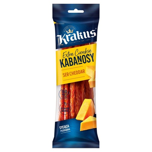 Pionowe opakowanie kabanosów Krakus Extra Cienkie Ser Cheddar. Opakowanie jest niebiesko-żółte z przezroczystym oknem, przez które widać brązowe, cienkie kabanosy. Obok nich widoczne są grafiki kawałków żółtego sera cheddar.