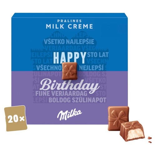 Produkt Milka Pralines Milk Creme, edycja "Happy Birthday", zawierający 20 sztuk. Opakowanie jest fioletowo-niebieskie z napisem "Wszystkiego najlepszego". Obok pudełka leżą dwie czekoladki, jedna w kształcie prezentu, druga przekrojona z mlecznym kremem.