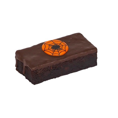 Ciemnobrązowy brownie o prostokątnym kształcie, obficie polany czekoladową glazurą, która spływa po bokach. Na środku widoczna jest pomarańczowa ozdoba z motywem czarnej pajęczyny i pająka.