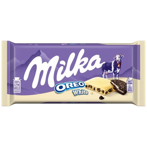 Fioletowo-białe opakowanie czekolady Milka Oreo White. Na etykiecie widnieje logo Milka, krowa Milka, góry oraz grafika przedstawiająca kawałek białej czekolady z kawałkami ciasteczek Oreo i przekrojone ciastko Oreo.