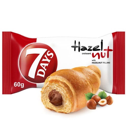 Rogalik 7 DAYS Hazelnut z nadzieniem orzechowym, 60g. Widoczny rogalik przekrojony, ukazujący ciemne nadzienie. Obok orzechy laskowe.