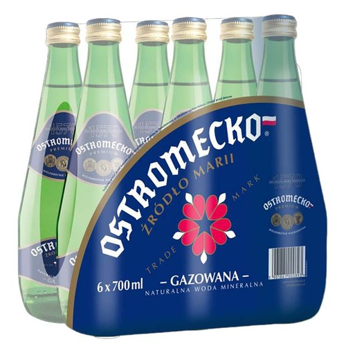 Opakowanie zbiorcze wody mineralnej gazowanej Ostromecko Premium. Zawiera 6 butelek po 700 ml, co daje łącznie 4.2 litra. Buteleczki są przezroczyste, z zielonkawym odcieniem, z niebieskimi etykietami i złotymi zakrętkami.