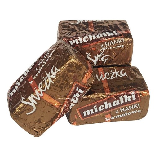 Trzy cukierki Michałki z HANKI karmelowe w brązowych, błyszczących opakowaniach. Każdy cukierek jest osobno zapakowany.